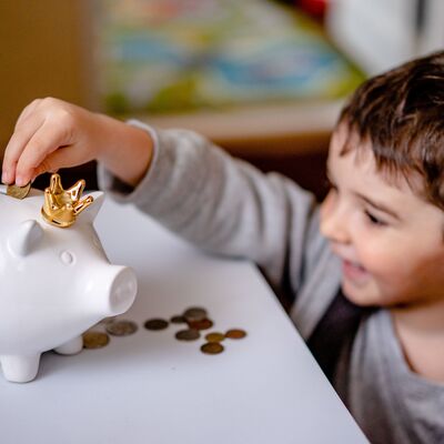 Kind wirft Geld in Sparschwein